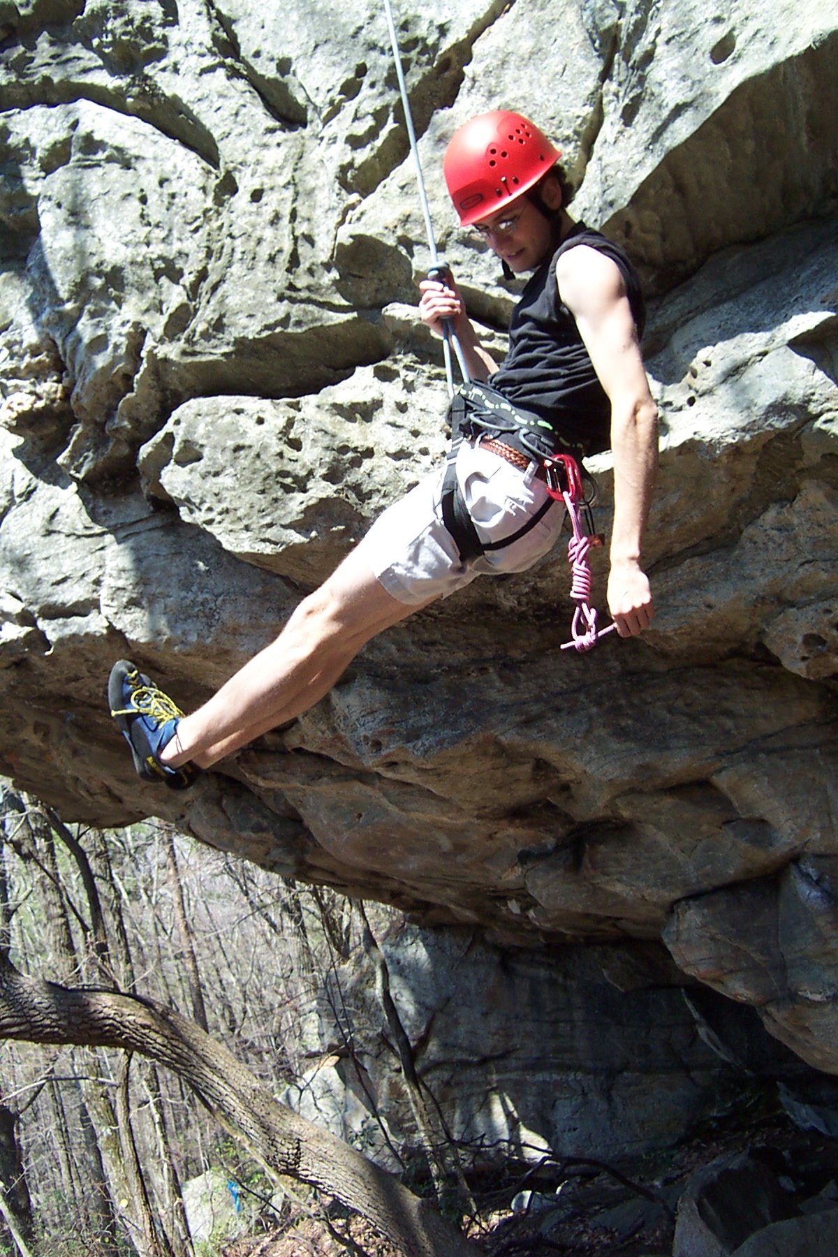 a man wearing a red helmet and safety gear climbing up a rock face