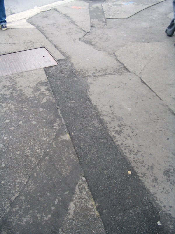 three people are walking along a paved sidewalk