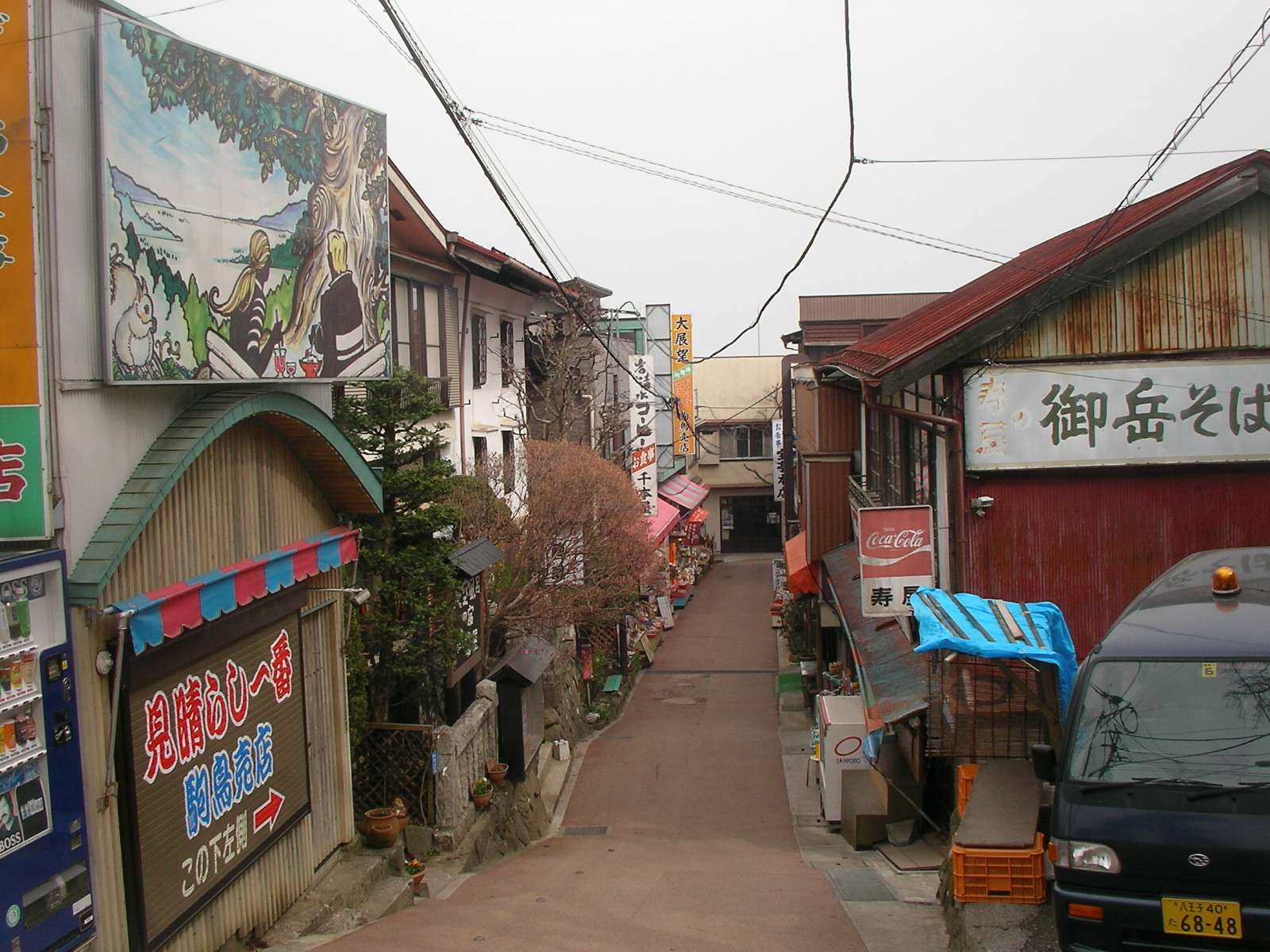an alley with a car and various business signs