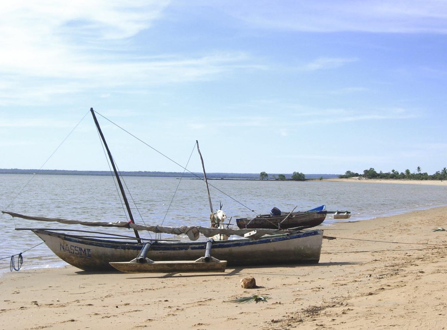 two boats sitting on top of a sandy beach