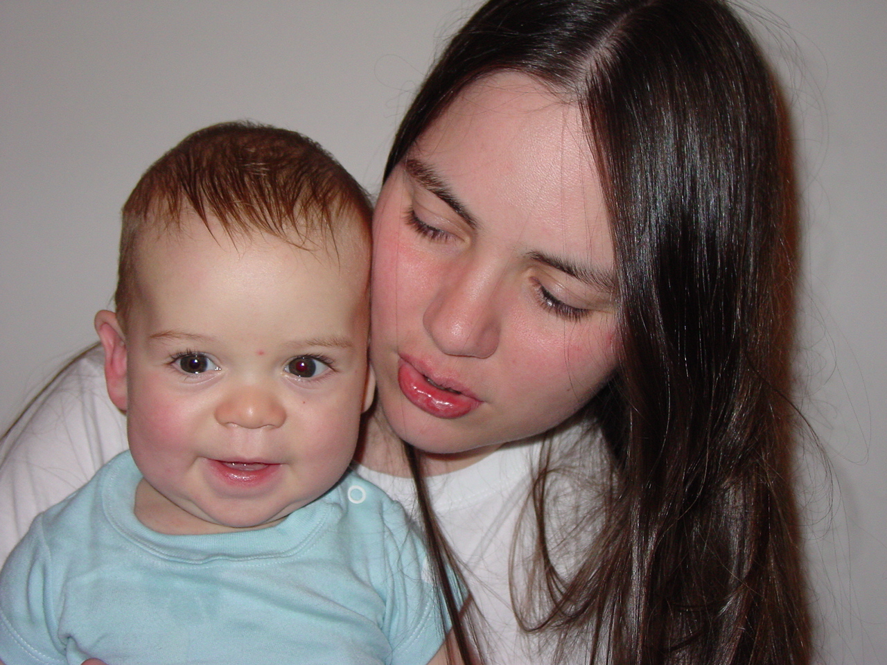 a woman holding a baby who has its face to her ear