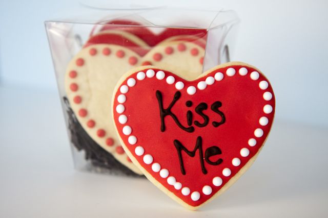 two cookies shaped like heart with'kiss me'written on them
