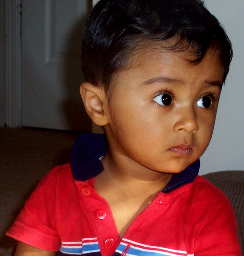 a child with short black hair wearing a red shirt