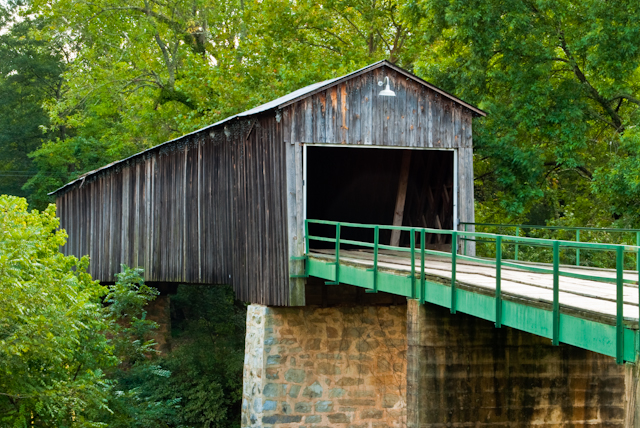 an old bridge with a green metal railings and brick wall