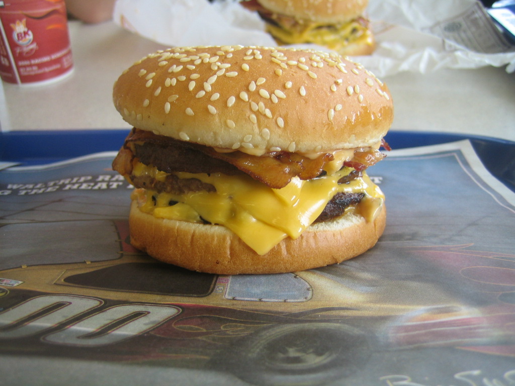 the hamburger on the table is topped with cheese and onions