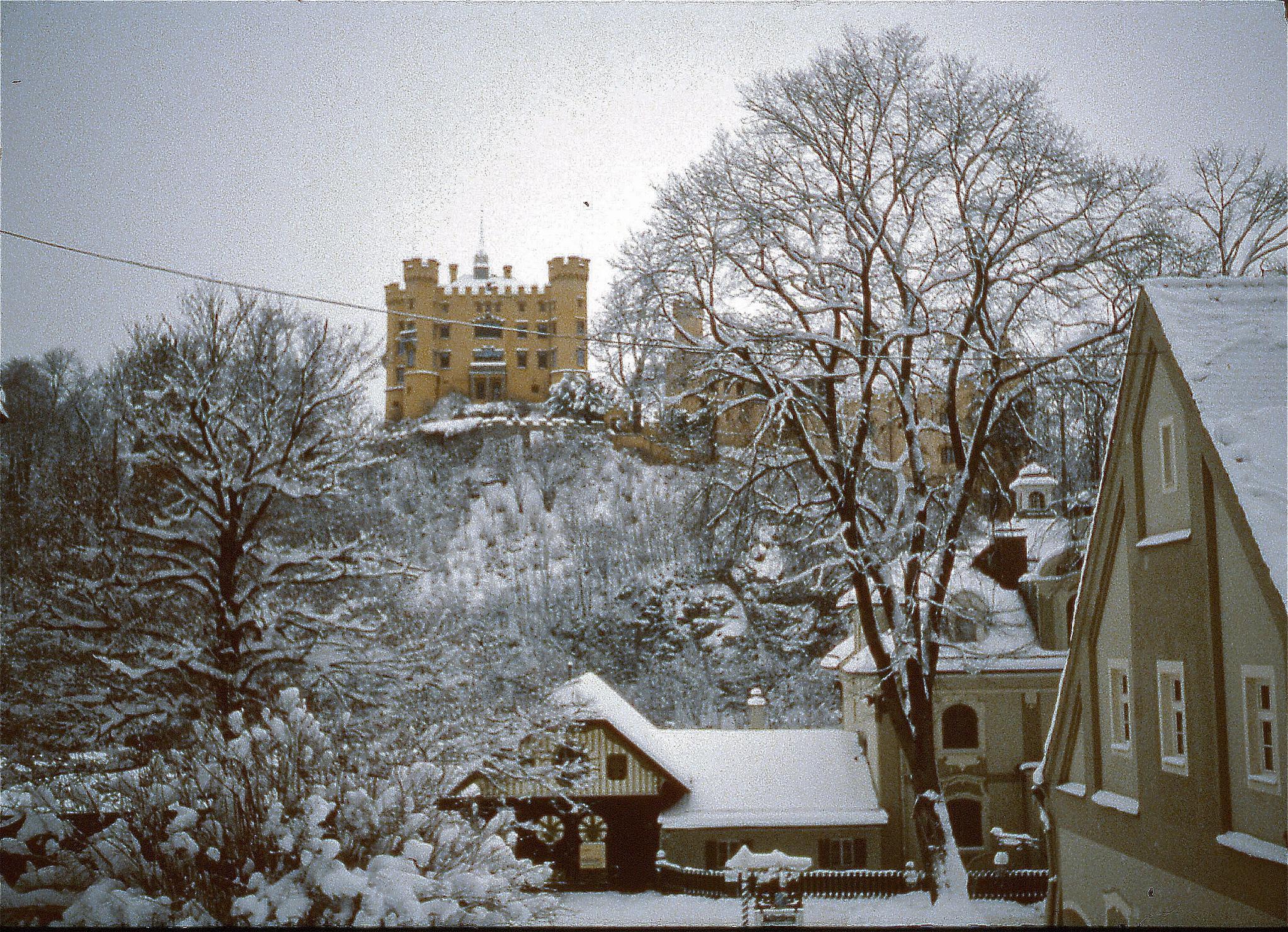 snow covered roofs and houses in front of a stone building