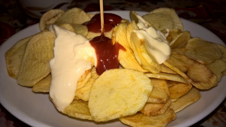 a plate filled with potato chips covered in ketchup and cheese