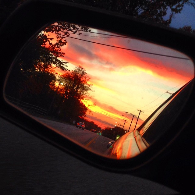 the reflection of a sunset in a side view mirror