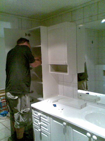a man installing a mirror in the bathroom