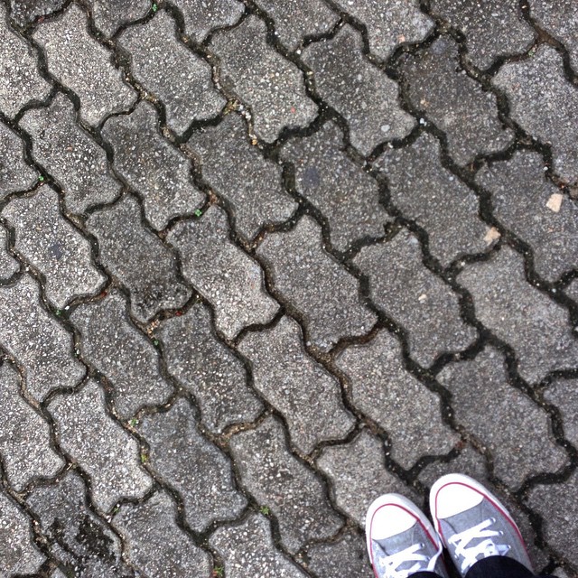 feet and sneakers are seen on a cobblestone