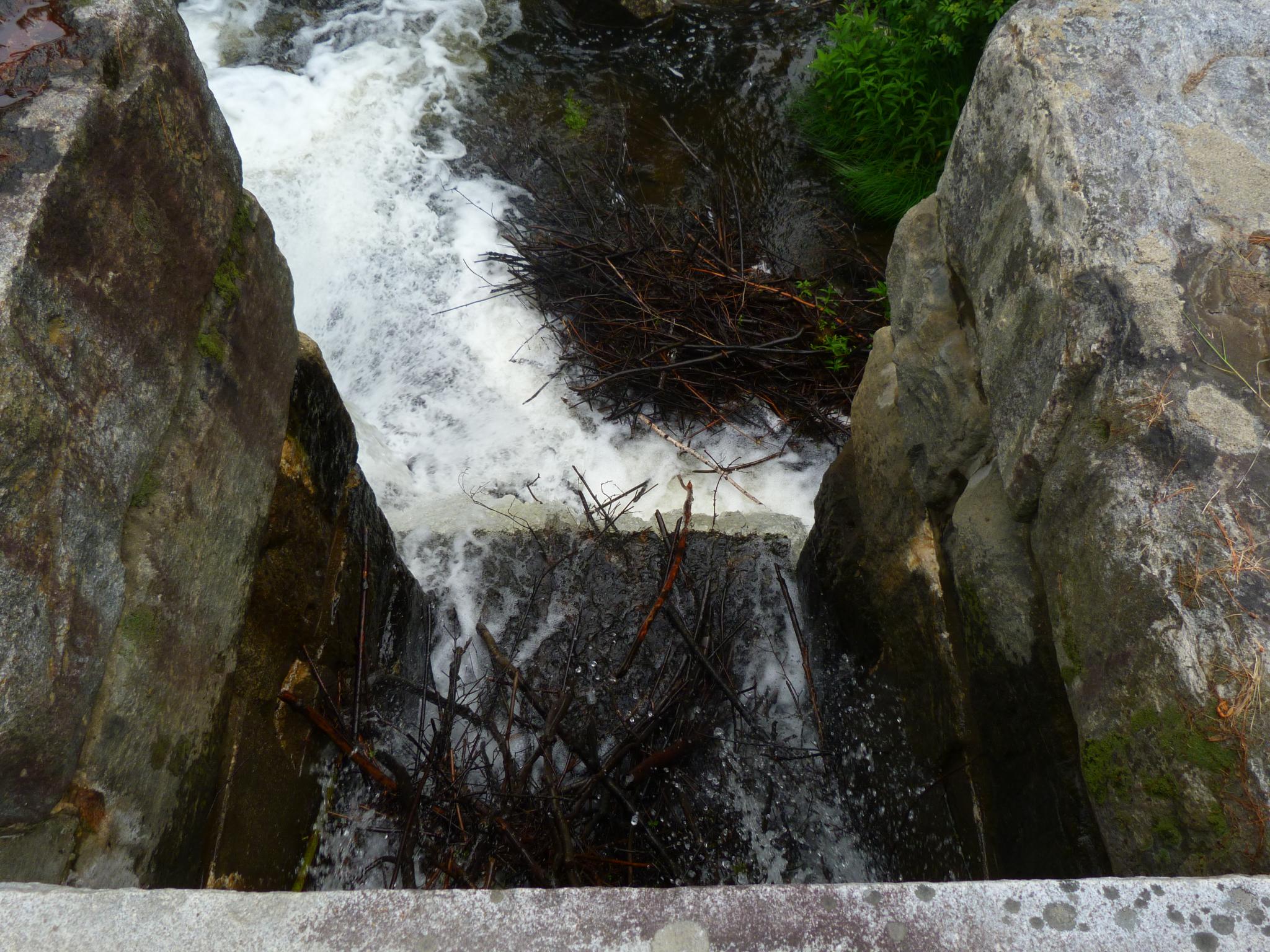 a waterfall flowing through a concrete ledge into a river