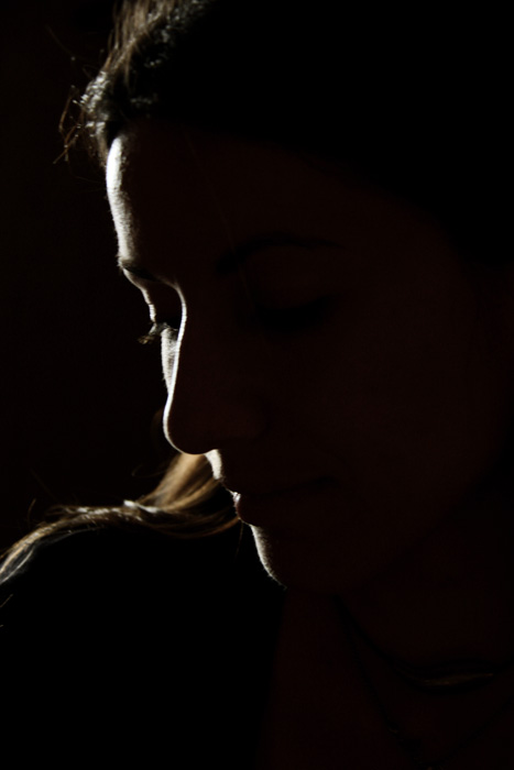 a dark silhouette of a woman with her hands on her face