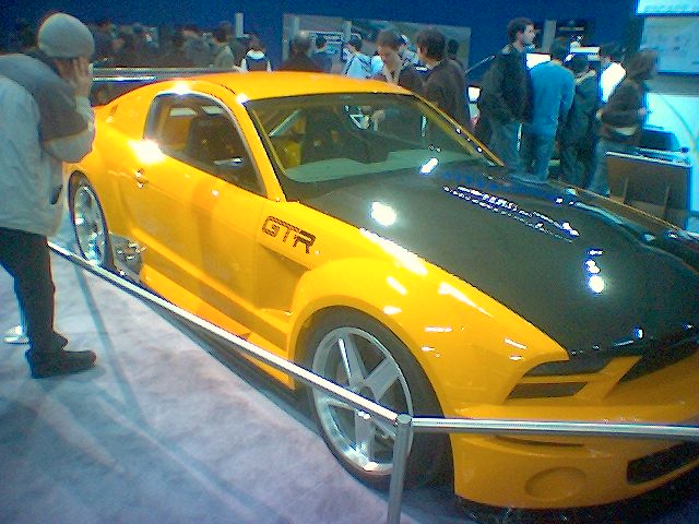 a yellow mustang car is parked on display at a show