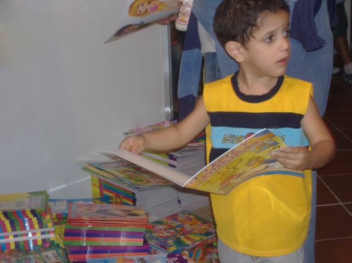 a  in a yellow shirt holds open a book