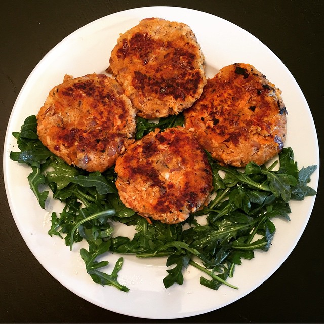 three crab cakes are placed on top of green leafy vegetables