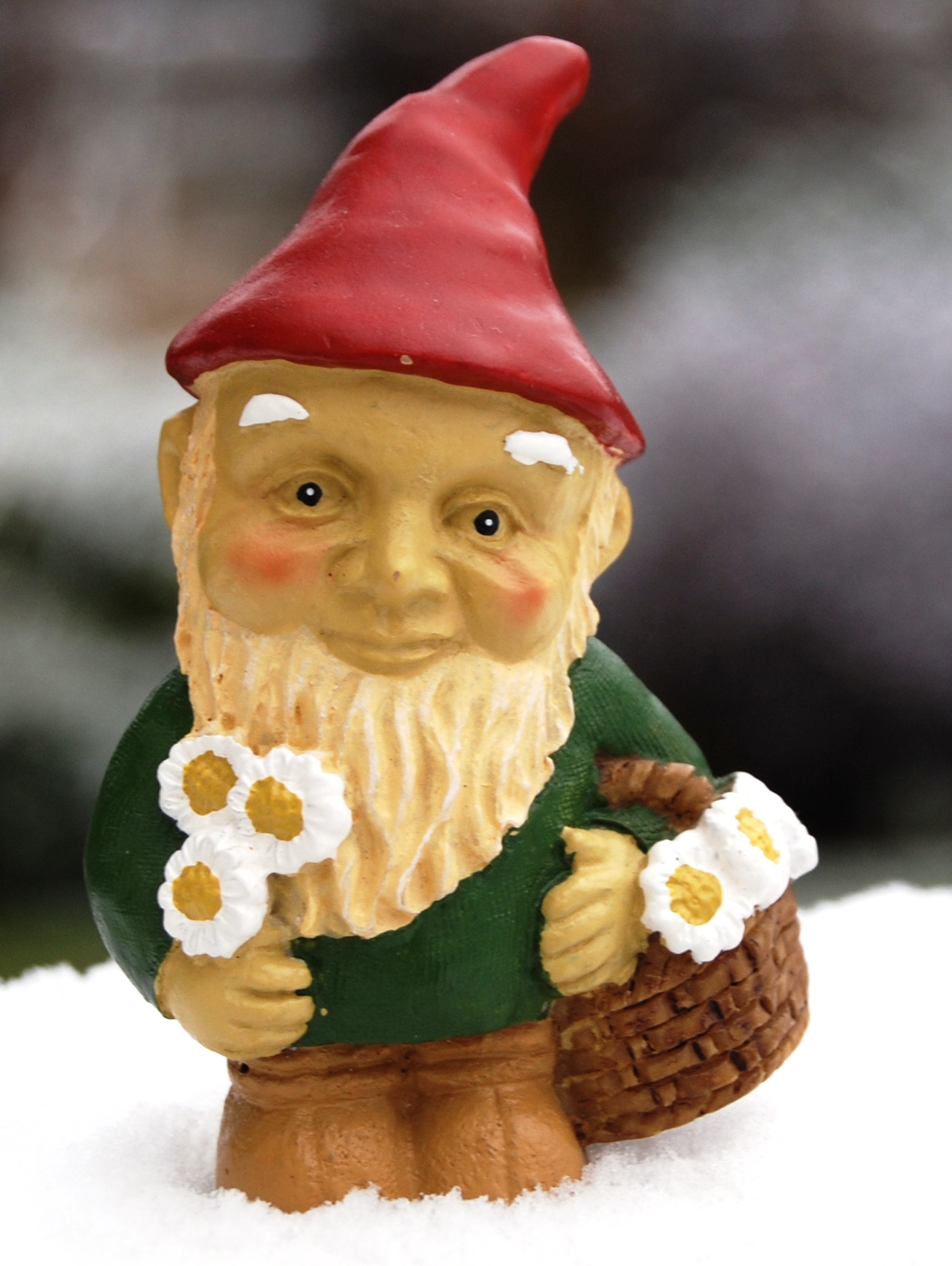 a small troll with flowers sits in the snow