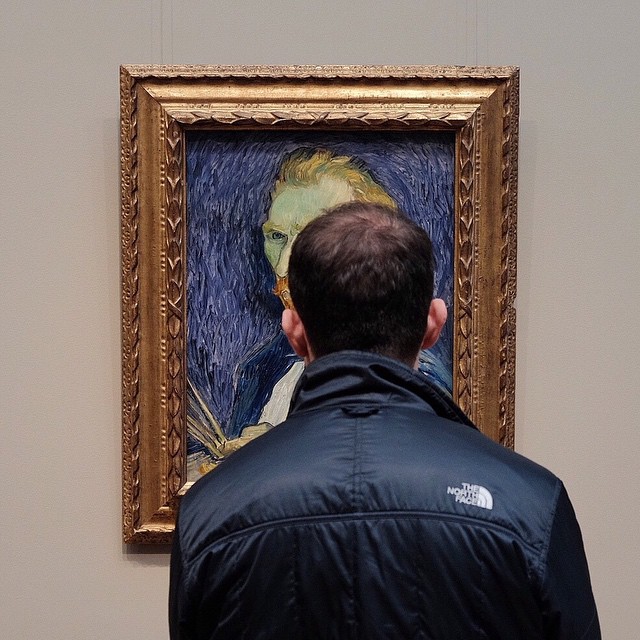 a man looking at a painting in a museum