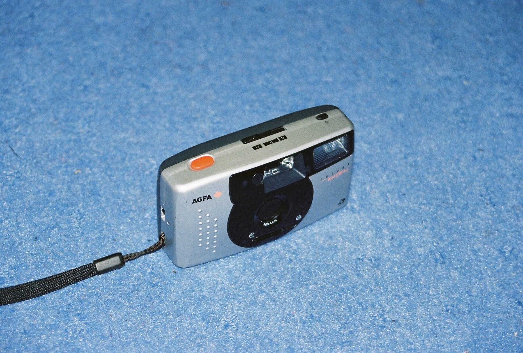 a camera sitting on a blue surface with an orange flash light attached