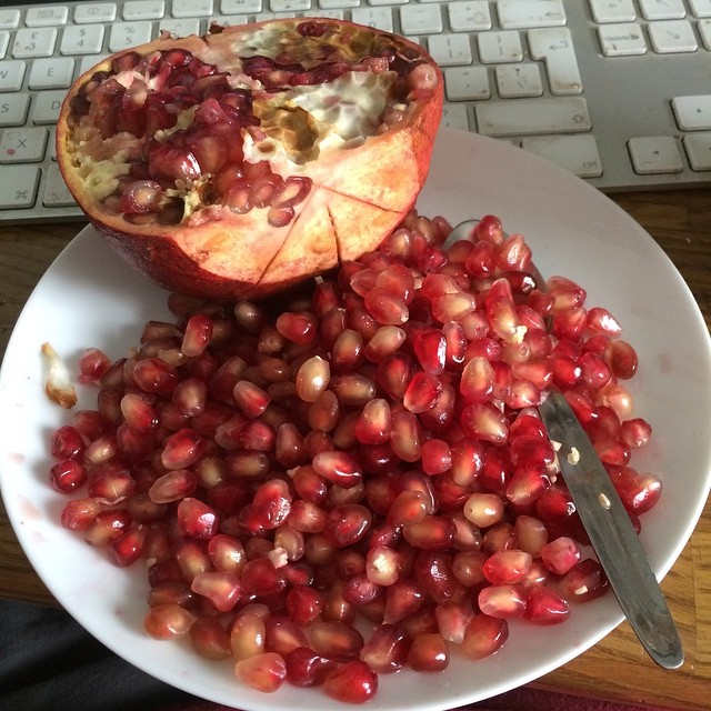 a plate filled with pomegranate next to a keyboard