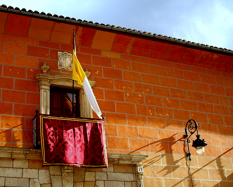 a colorful flag hangs on a brick building next to a window