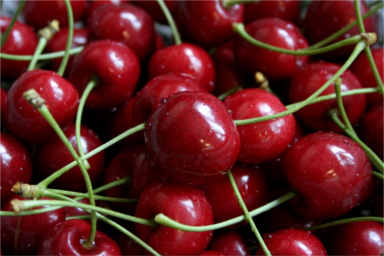 a pile of cherries with water droplets