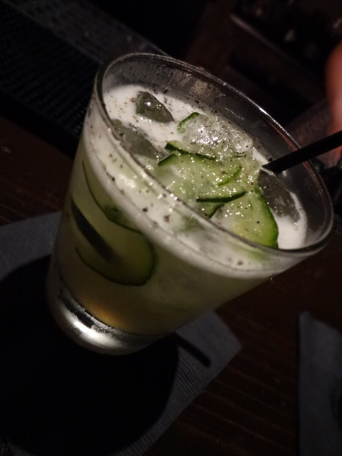 a glass of cucumber cocktail and a person