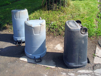 three water tanks are sitting on the side of the road