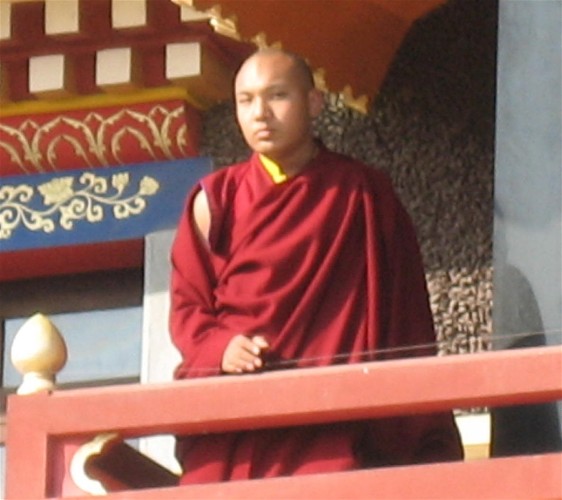 a man with a red monk outfit looking over a fence
