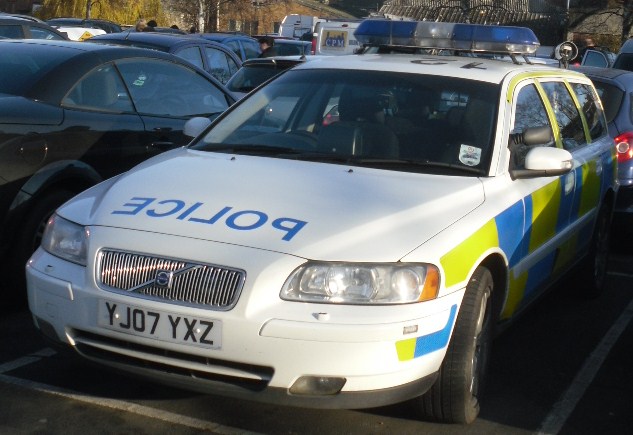 a police car parked next to a row of parked cars