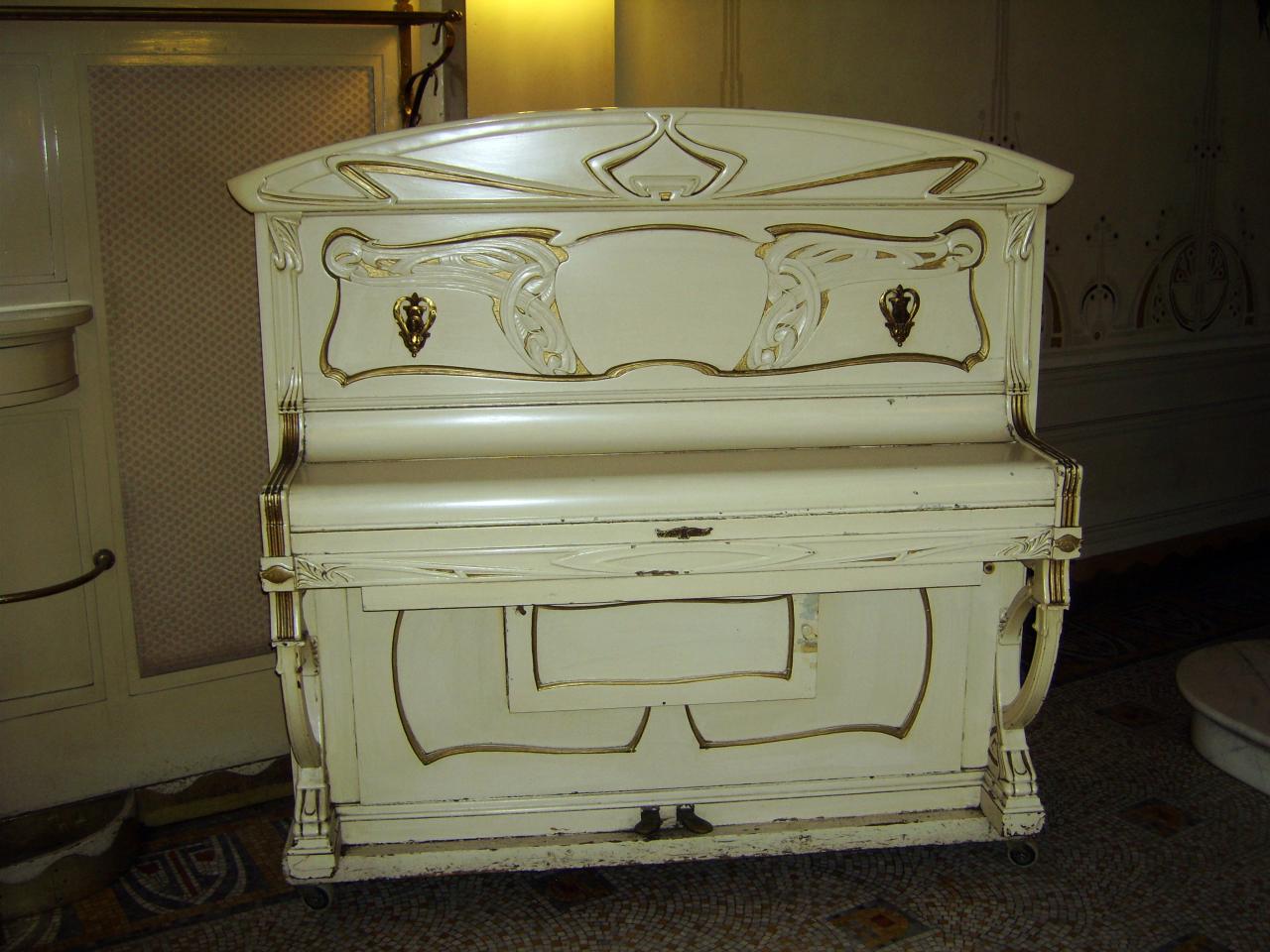 an old white piano with fancy carvings and decoration