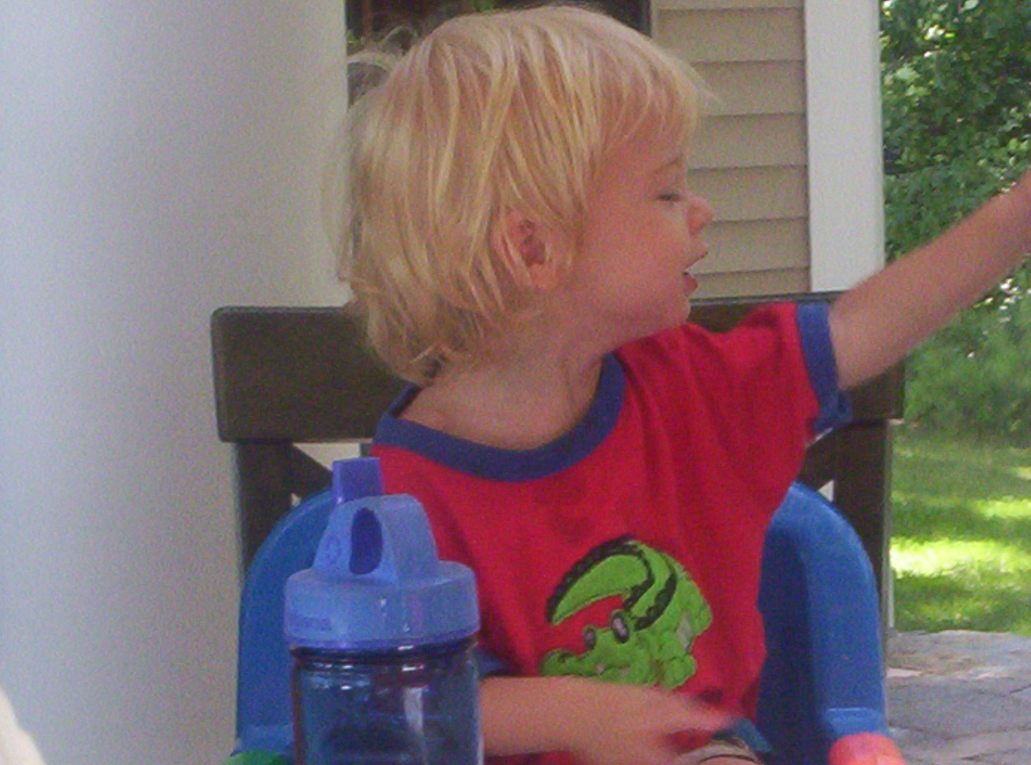little blond boy sitting on chair holding a blue water bottle