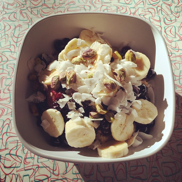 the bowl is full of granola, nuts and bananas
