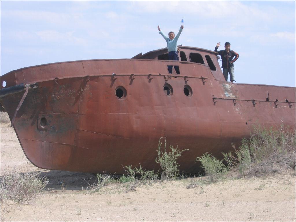 three men standing on top of a rusty boat