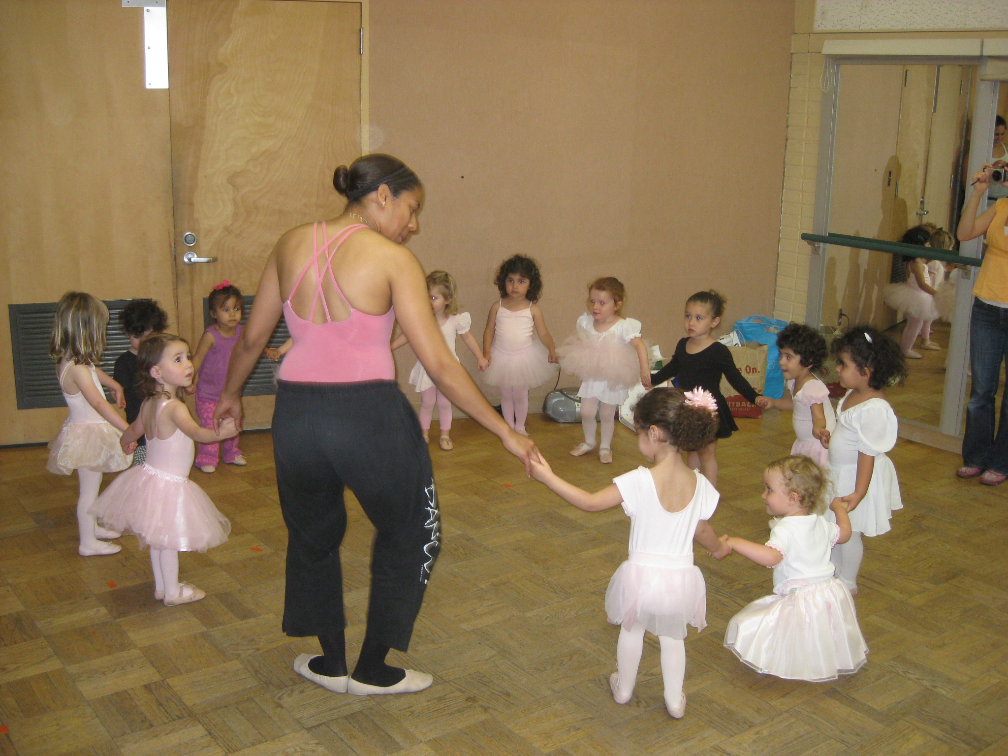 an adult is leading a group of dancers in a dance studio