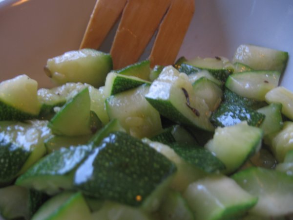 zucchini slices are sitting in a bowl with a wooden fork
