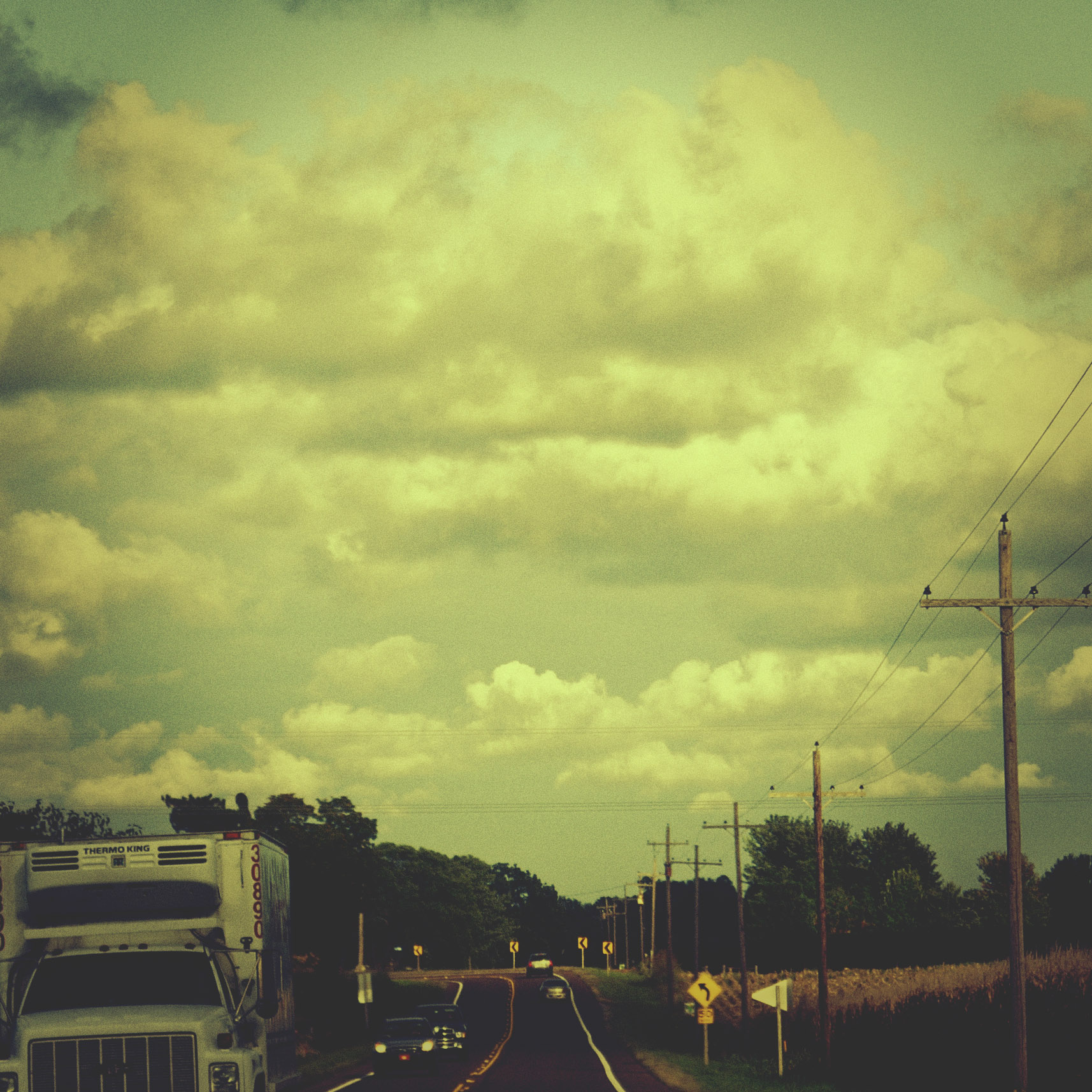 a truck and tractor drives down the highway in the countryside