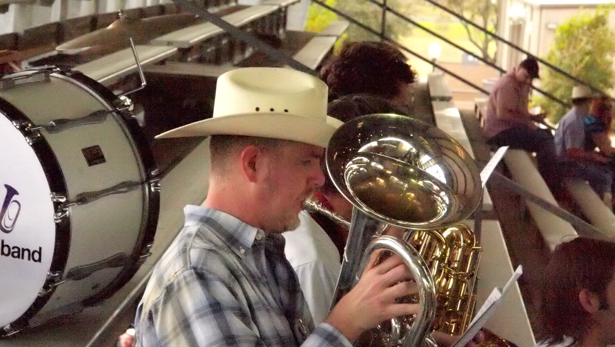a man with a hat plays the trumpet in front of people in a band