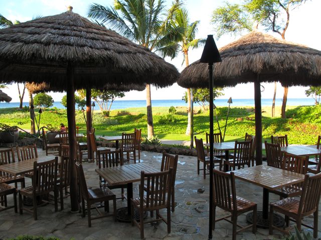 an outdoor area with many tables and chairs covered by straw umbrellas