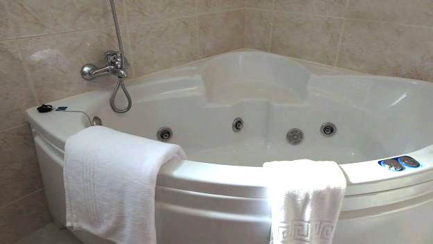 a white bath tub with white towels hanging from the shower head