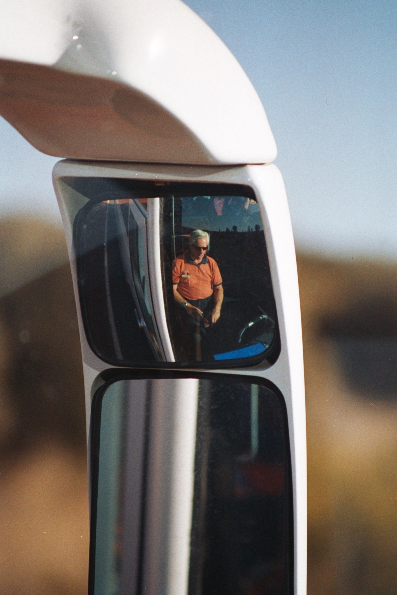 a side view mirror shows the reflection of a man on a bicycle