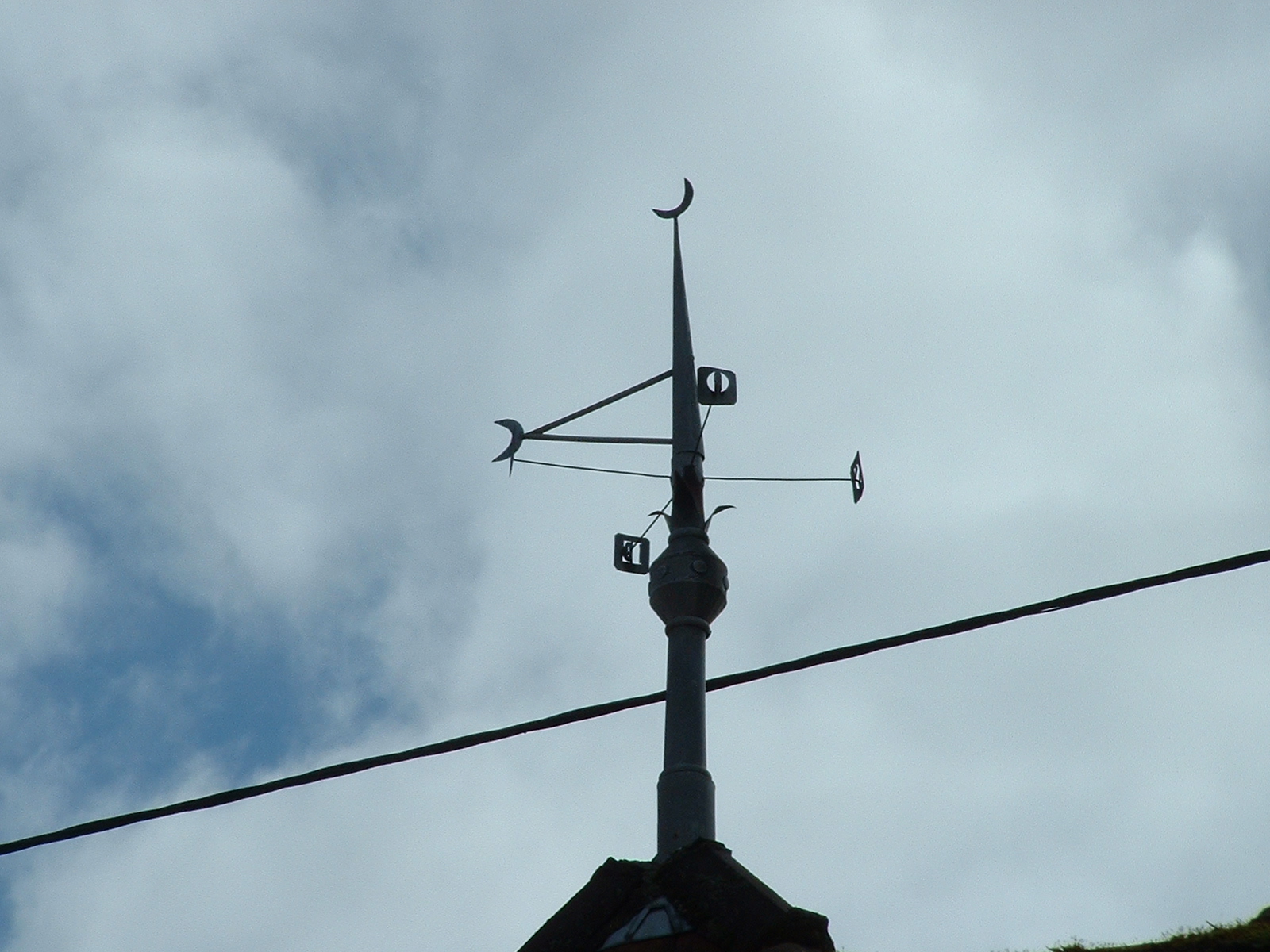 an electronic telephone tower attached to wires under cloudy skies