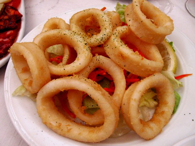 onion rings are on a plate near bowls of food
