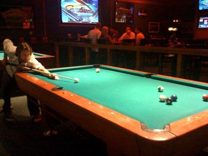 a young man is leaning over a pool table to look at soing