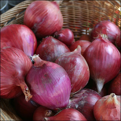 several red onions in a basket on display