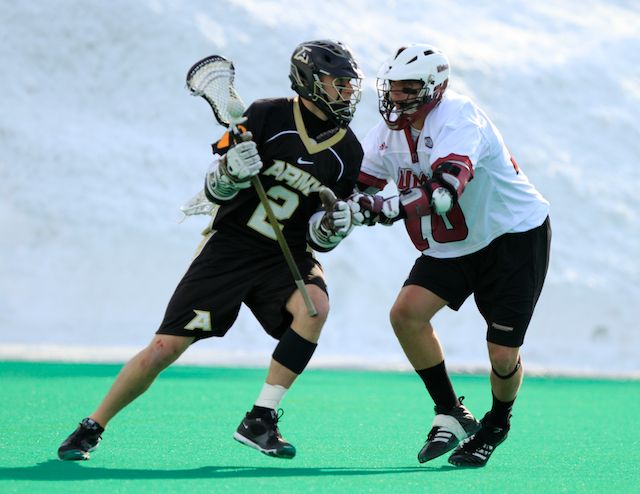 a lacrosse player runs with the ball while the opposing team defends him