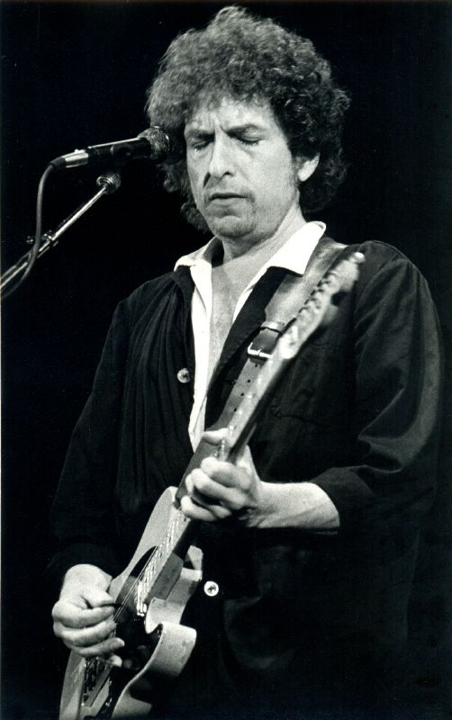 an older man playing a guitar with his face obscured by a microphone