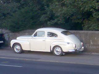 a white classic car parked on the side of a road