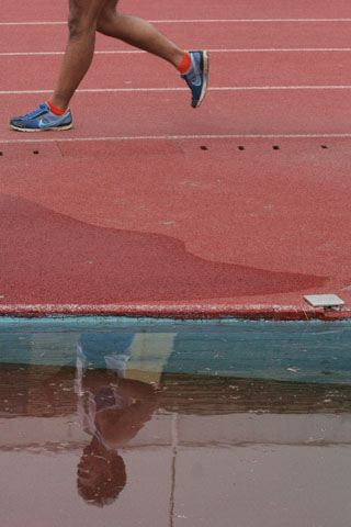 the woman is wearing a blue shoe, jogging on the race track