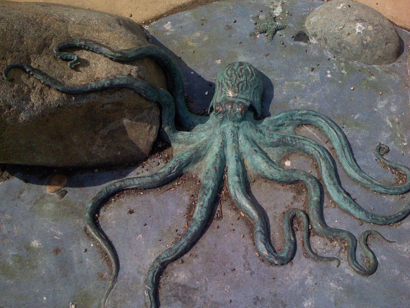 an octo sculpture sitting on the ground by rocks