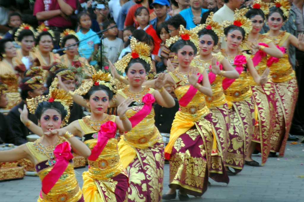 girls in gold and red dresses with pink leis doing dance